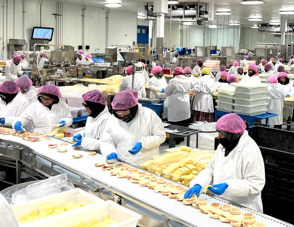 Associates on the facility floor with pink hairnets on for October Breast Cancer Aawareness